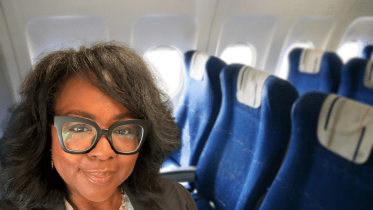 Tomiko Harvey smiling in front of rows of blue airplane seats, from her viral story about refusing to switch seats on a plane