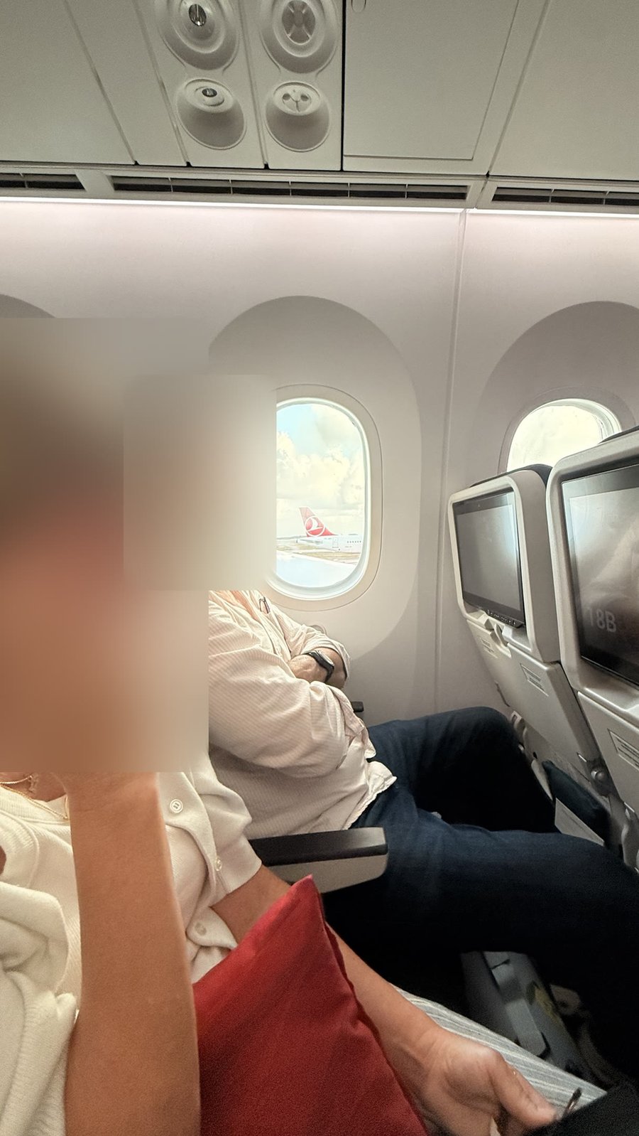 Fellow passengers in my row, faces blurred, on a 10-hour flight from Istanbul to Washington, D.C.